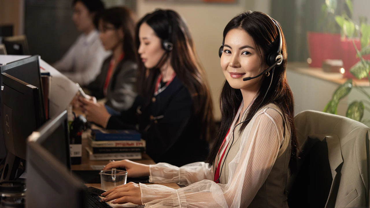 Customer service agent wearing a headset at a desk in an open-plan office