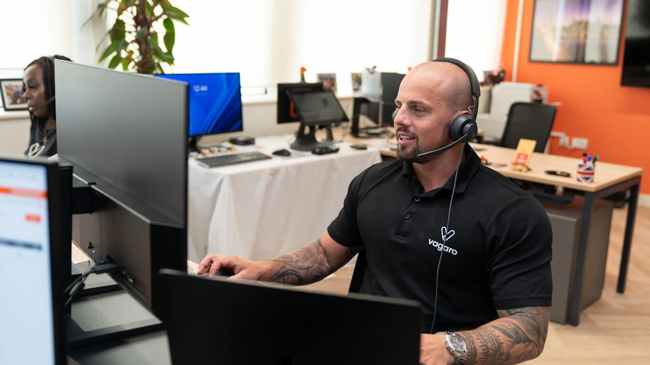 Support agent working at a desk with two monitors and a headset