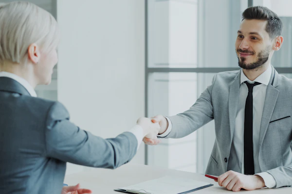 Two professionals shaking hands across a table in an office