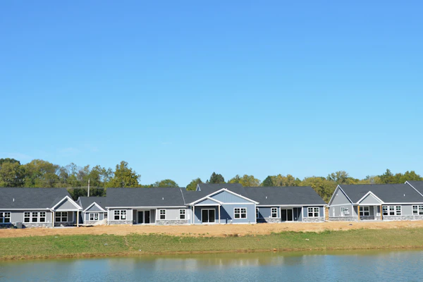 Row of modern houses beside a calm lake, representing property listings