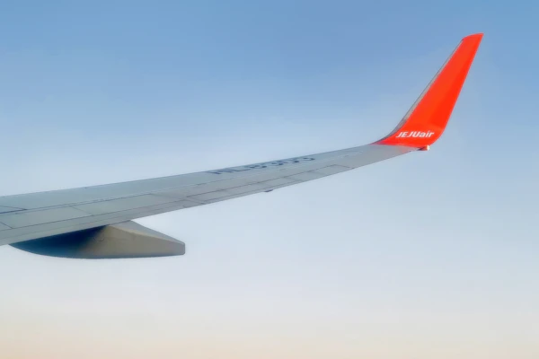 Airplane wing above the clouds against a clear sky