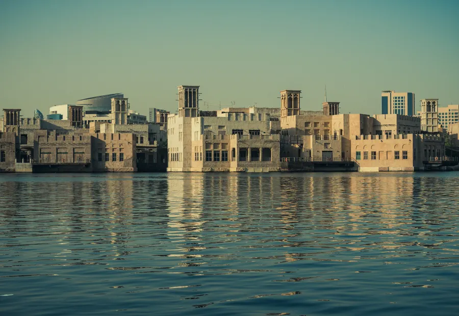Traditional wind-tower buildings reflected in the water of Dubai Creek at sunset
