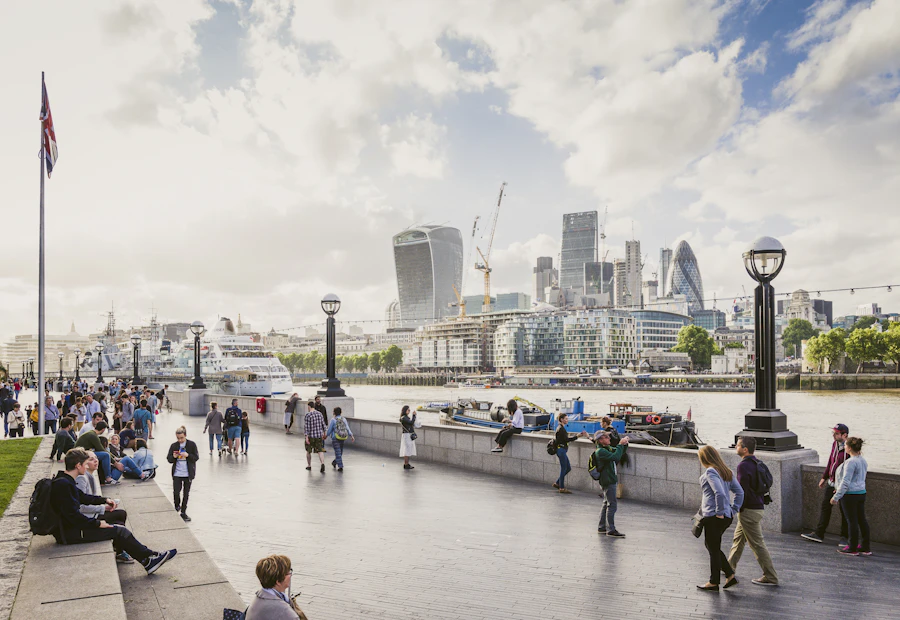People walking along the South Bank with the City of London across the Thames