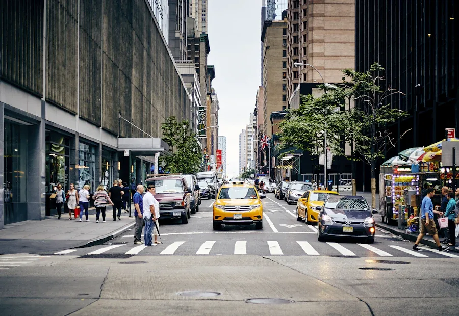 Pedestrians crossing a Manhattan street between tall buildings