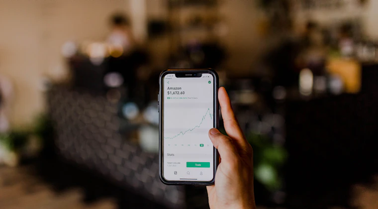 A hand holding a phone showing stock market data
