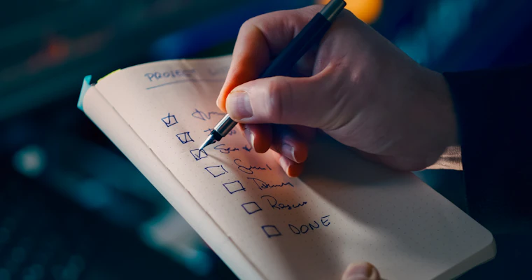 Hand checking off items on a printed checklist