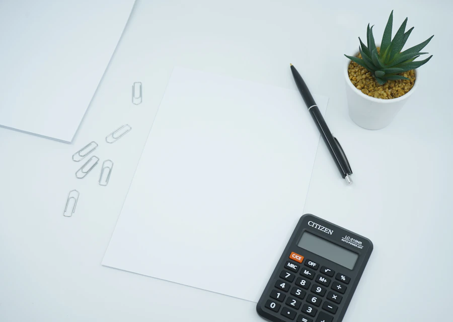 Calculator and pen resting on a blank sheet of paper