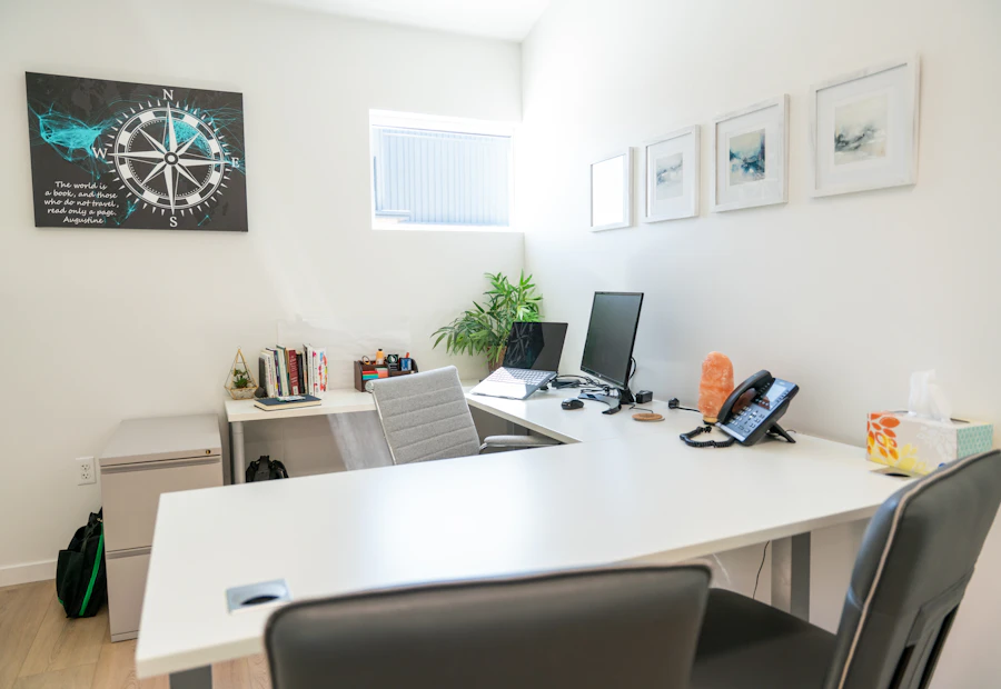 Modern office workspace with dual monitors, bookshelves and a plant