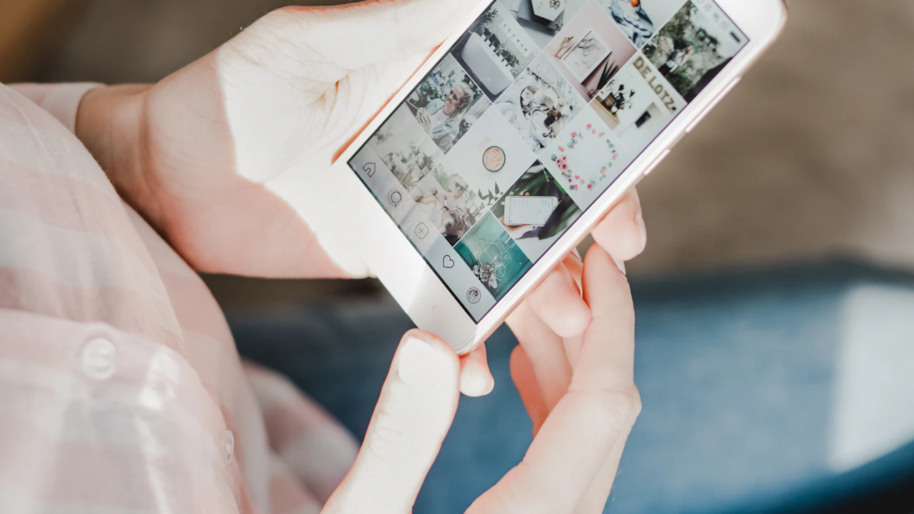 Person holding a phone showing an Instagram profile grid