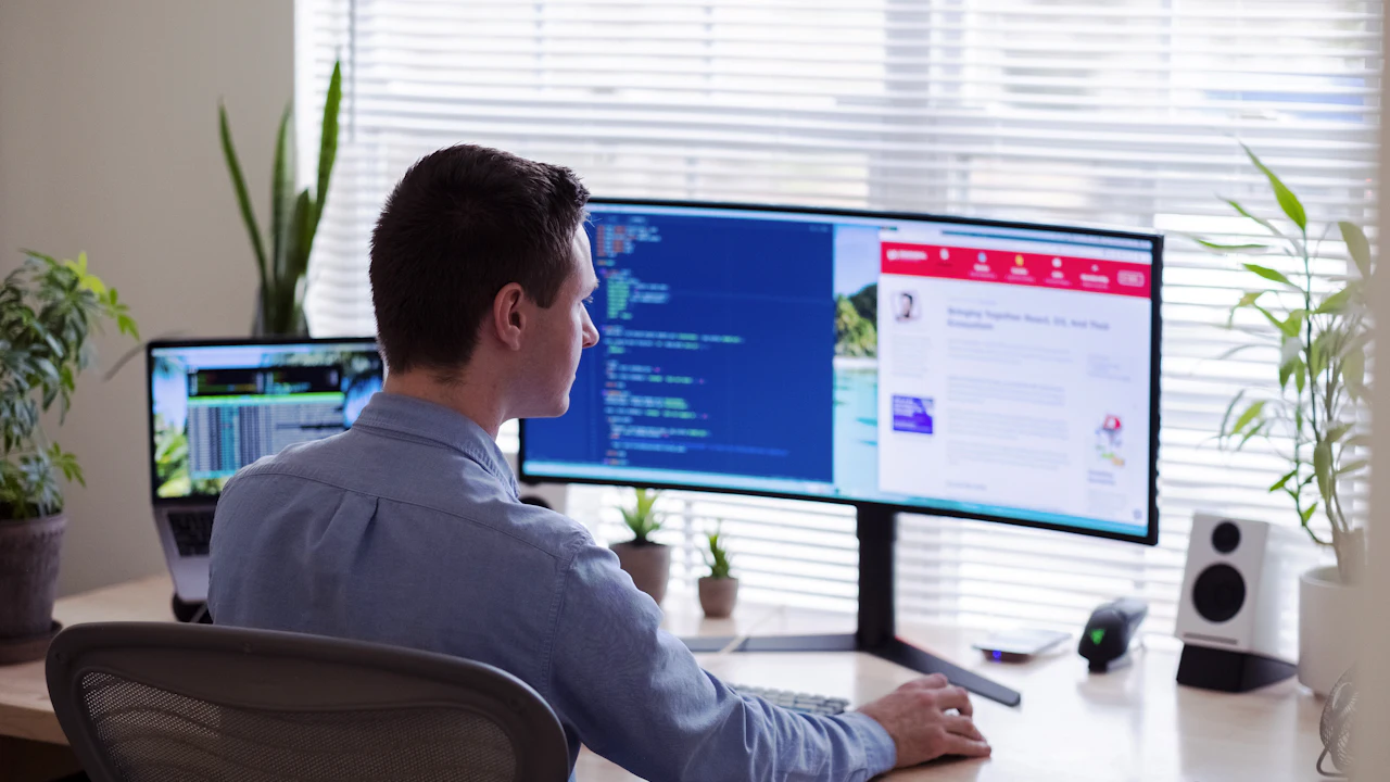 Developer at a curved monitor with code and a live website side by side