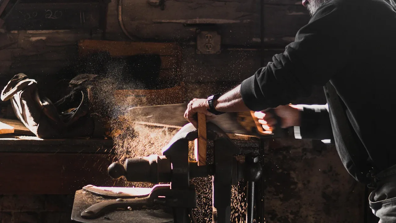 Craftsman sawing a length of timber at a workbench in a workshop